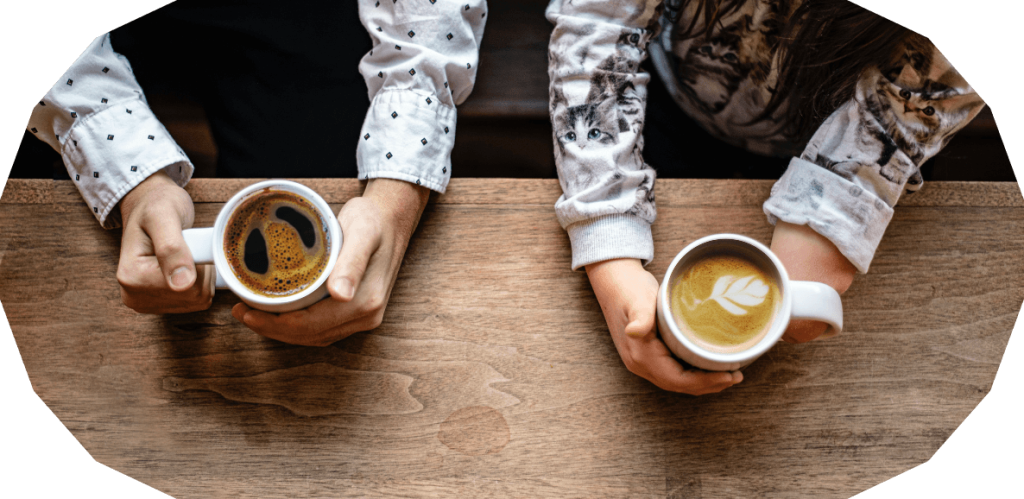 Close-up of two women’s hands holding cups of tea, symbolising empathy, listening, and supportive conversations.