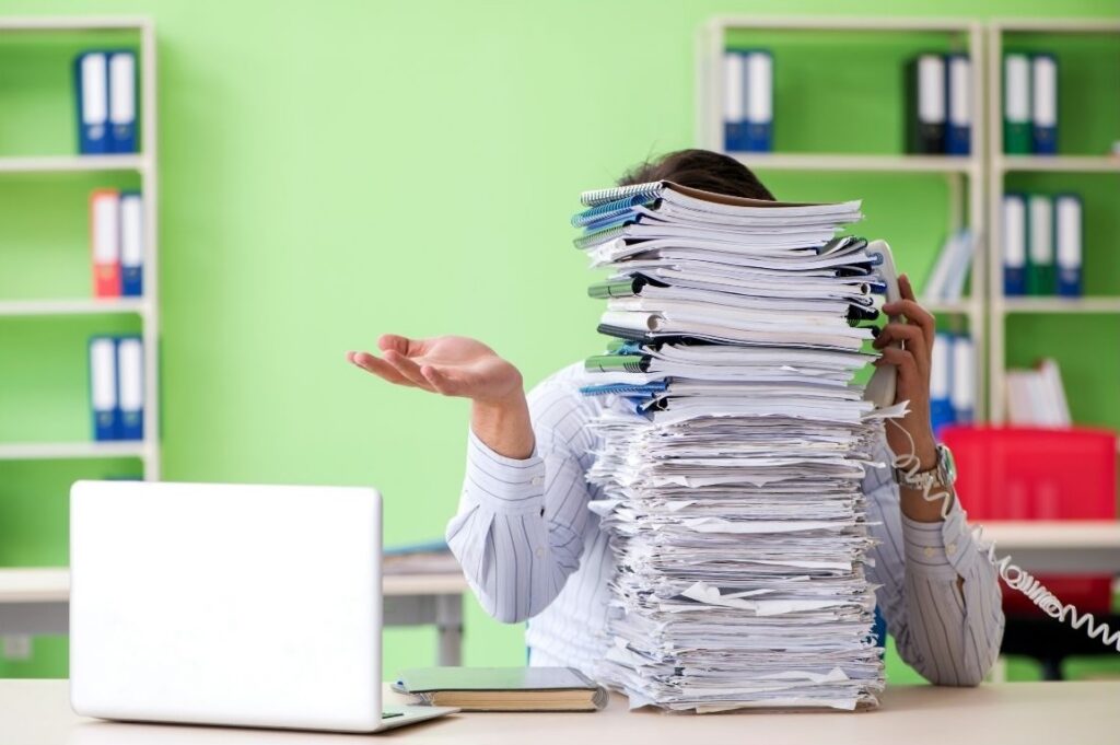Woman sitting at a desk surrounded by paperwork and clutter